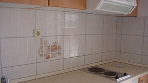 Una cocina con azulejos blancos, un lavabo, una estufa y armarios de madera.