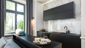 Eine moderne Küche mit Einbauofen, Spüle und Marmorfliesenspiegel. Ein Essbereich mit einer Couch und einem Tablett mit Tassen und einem Teekessel.