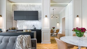 Eine moderne Küche mit Einbauherd, ein Essbereich mit rundem Tisch und Stühlen sowie ein Wohnzimmer mit Sofa und Couchtisch.