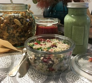 A table with a glass jar containing a salad, a glass jar with a red mixture, and a green smoothie bottle. - PAULOVE Apartments (Kraków)