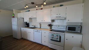 A compact kitchen with white cabinets, a dishwasher, a stove, and a microwave. - Calypso unit 701 located at 62nd street and Ocean front (Ocean City)
