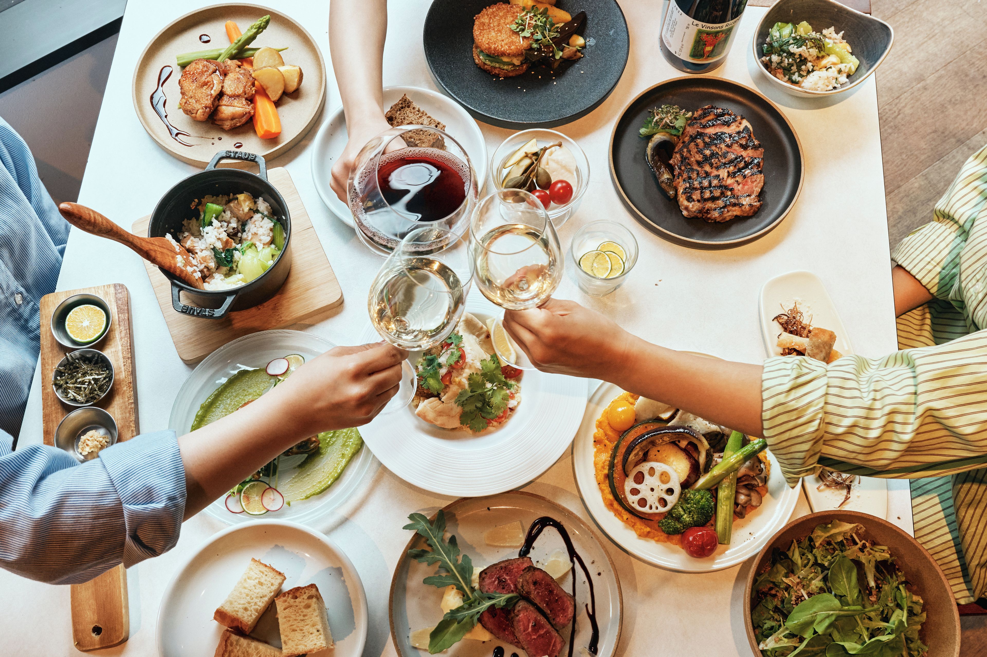 A dining table with various dishes, glasses of wine, and a bottle of wine.