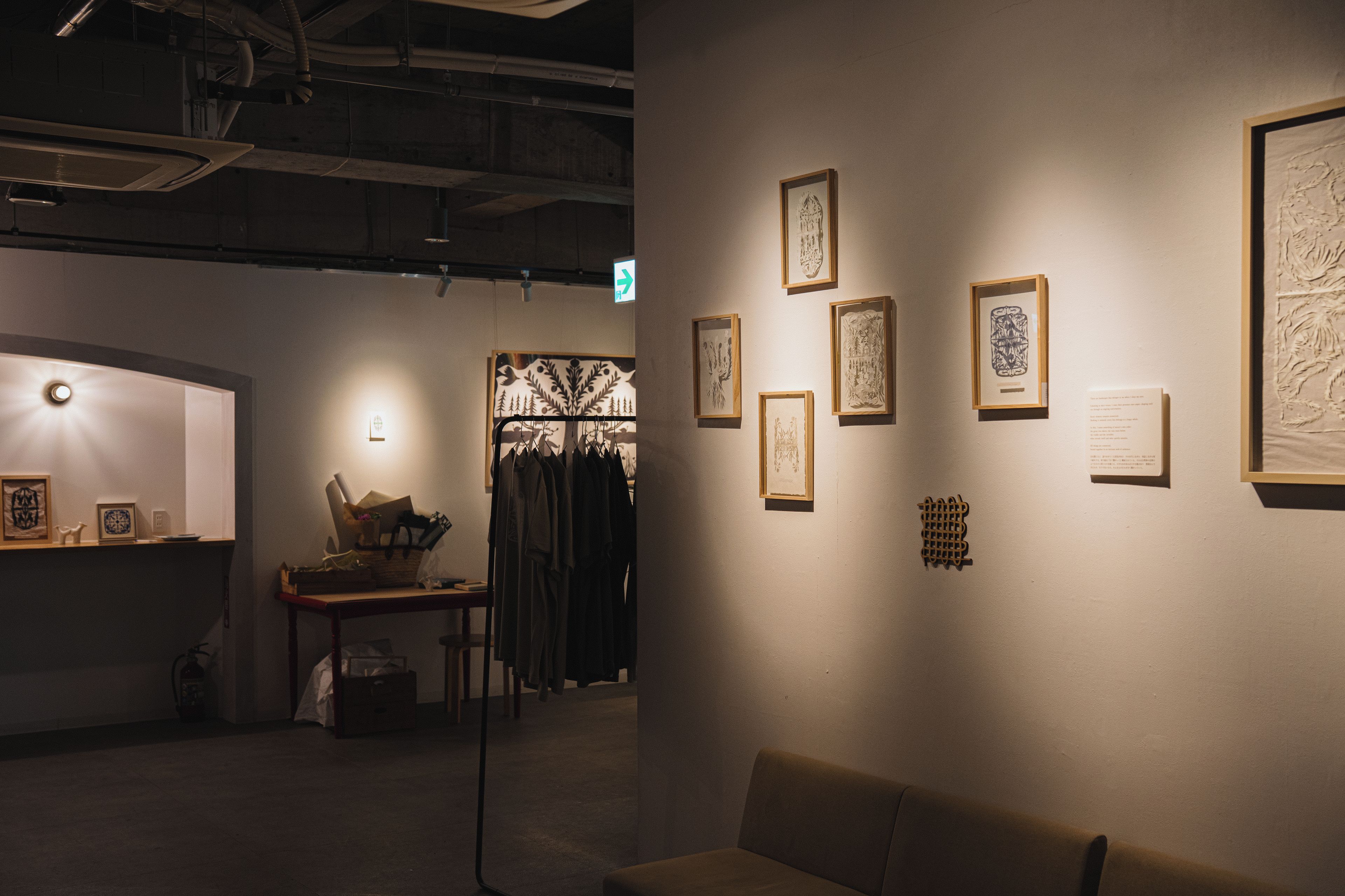 Eine Kunstgalerie mit gerahmten Kunstwerken an den Wänden, einem Empfangstisch und einer Sitzgruppe.