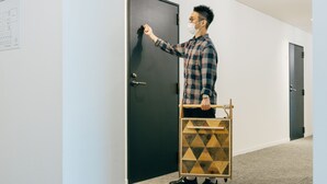 A person in a plaid shirt opening a door with a wooden cart. - WPÜ HOTEL HAKONE (Hakone)