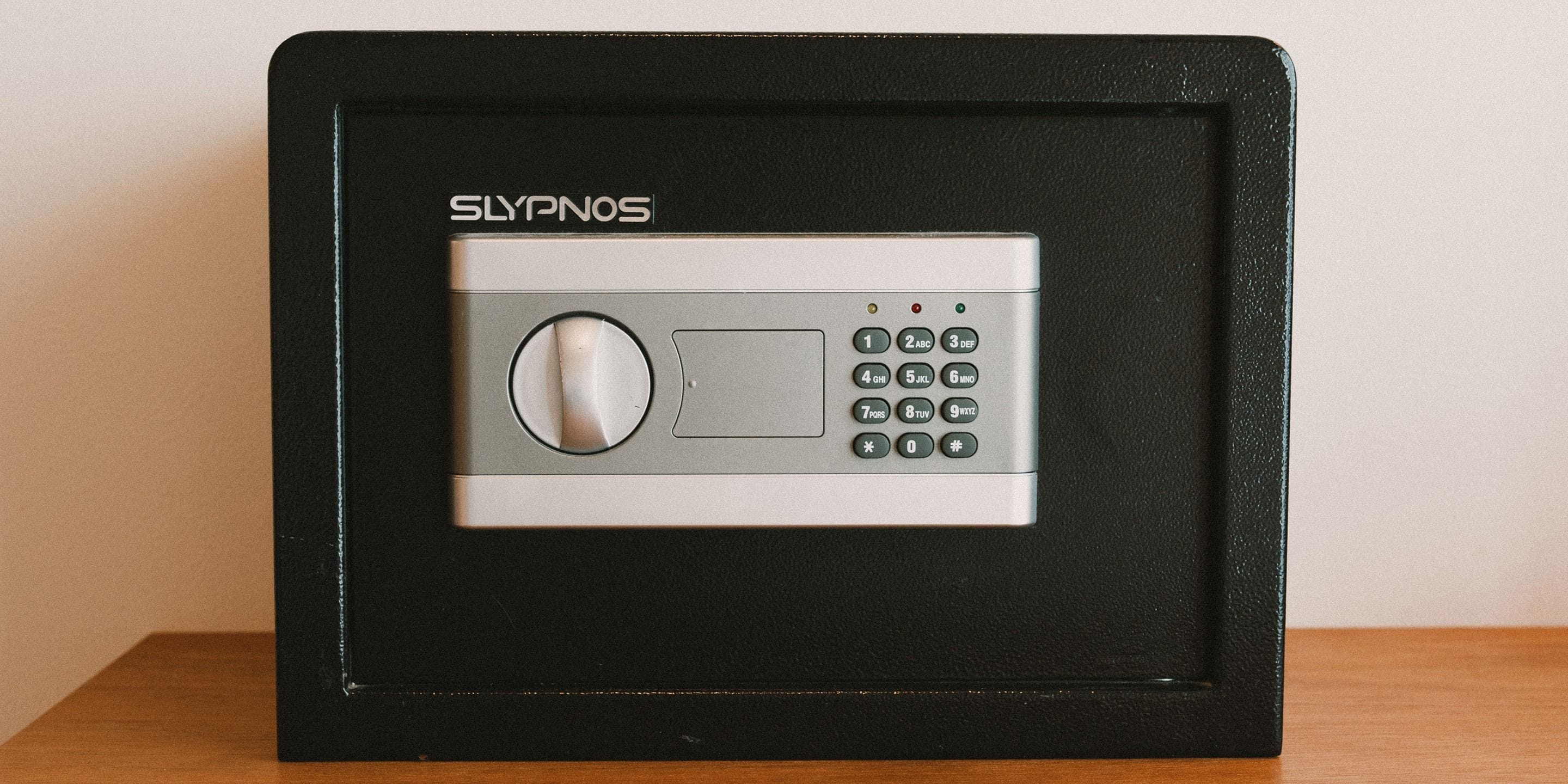 A black-framed electronic keypad lock labeled 'SLYPNOS' with a circular dial and a numeric keypad.