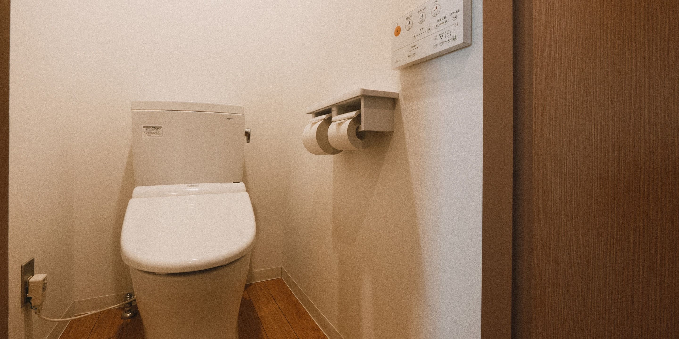 A toilet with a paper towel dispenser mounted on the wall.
