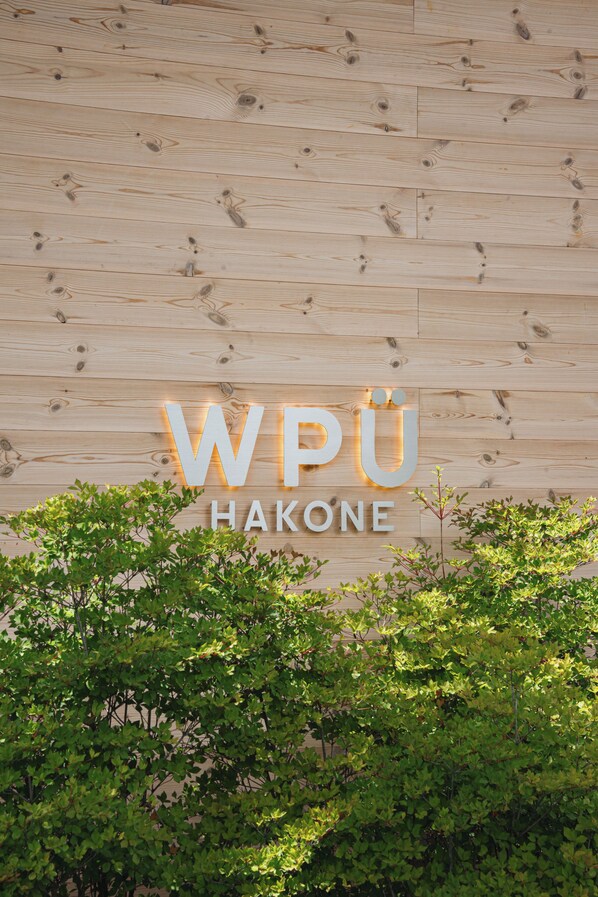 Pared de madera con el texto 'WPÜ HAKONE' iluminado con luces.