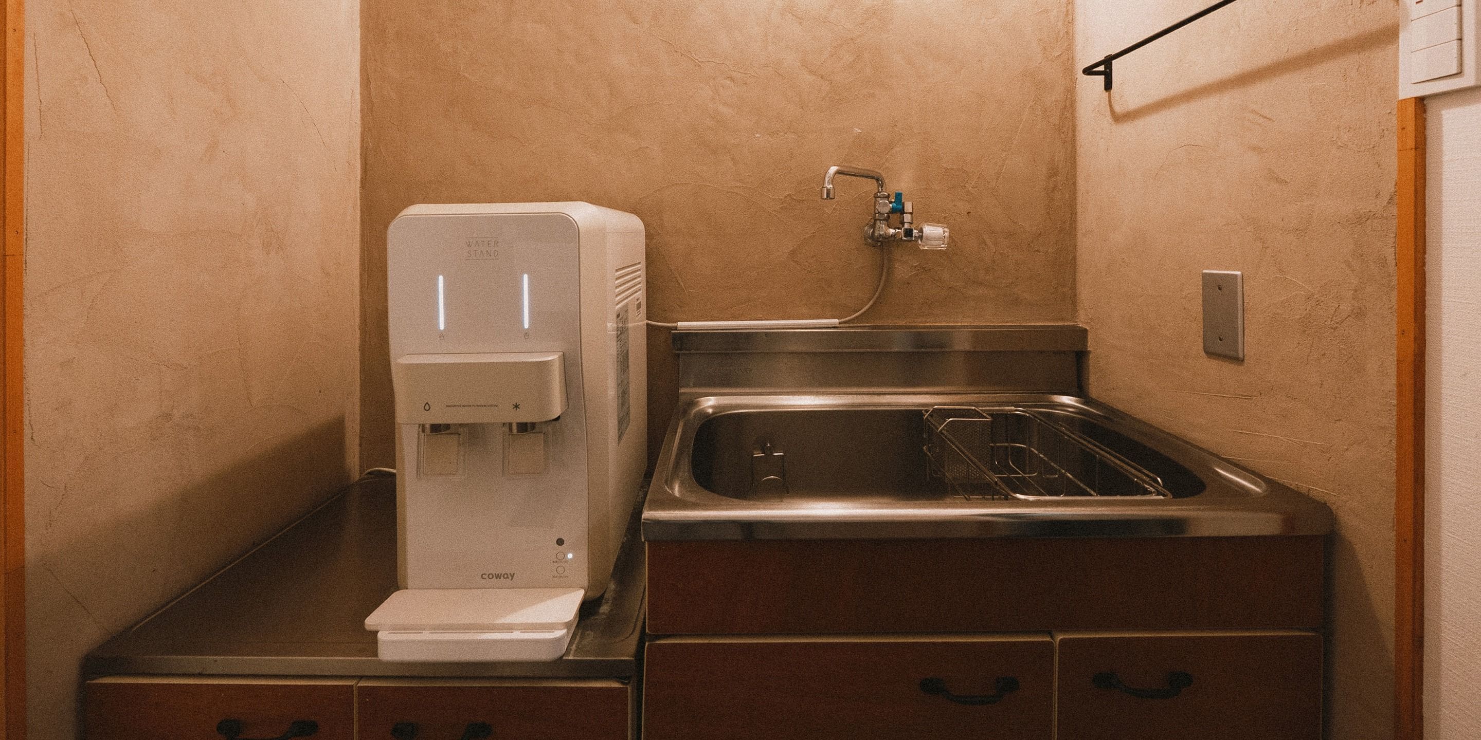 A compact kitchenette with a built-in water dispenser, a stainless steel sink, and a small countertop.