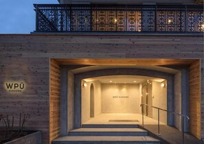Entrada de un edificio con fachada de madera, baranda de metal y un cartel que dice 'WPÜ HAKONE'.