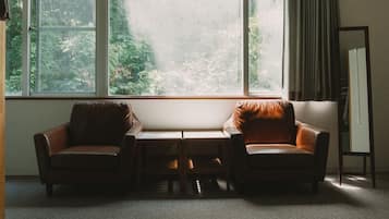 Una habitación con dos sillones de cuero, una mesita y un ventanal con vistas a zonas verdes.