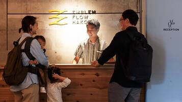 A reception desk with a wooden panel design, a sign reading "EMBLEM FLOW HAKO", and a reception area marked with a sign.