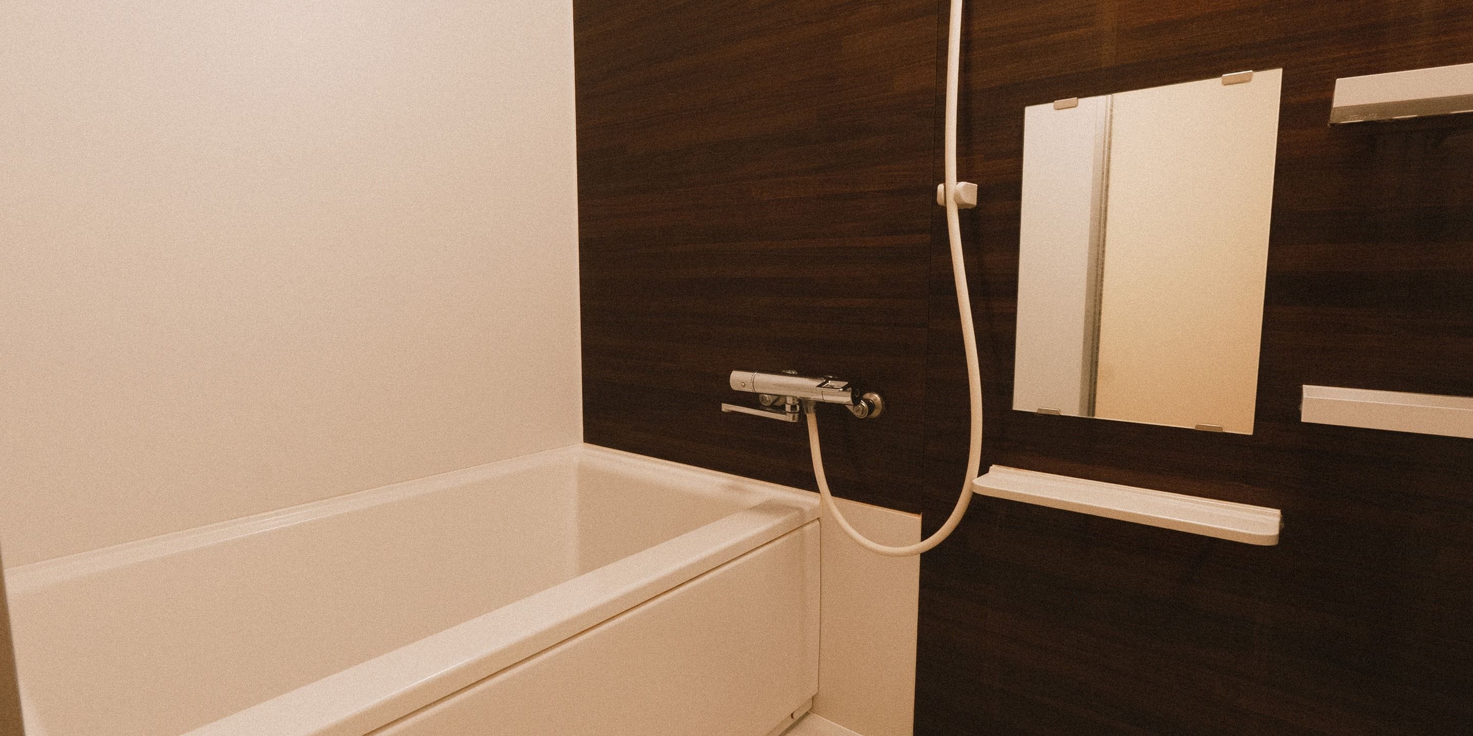 Un baño con una bañera blanca, una pared de madera oscura y un espejo.