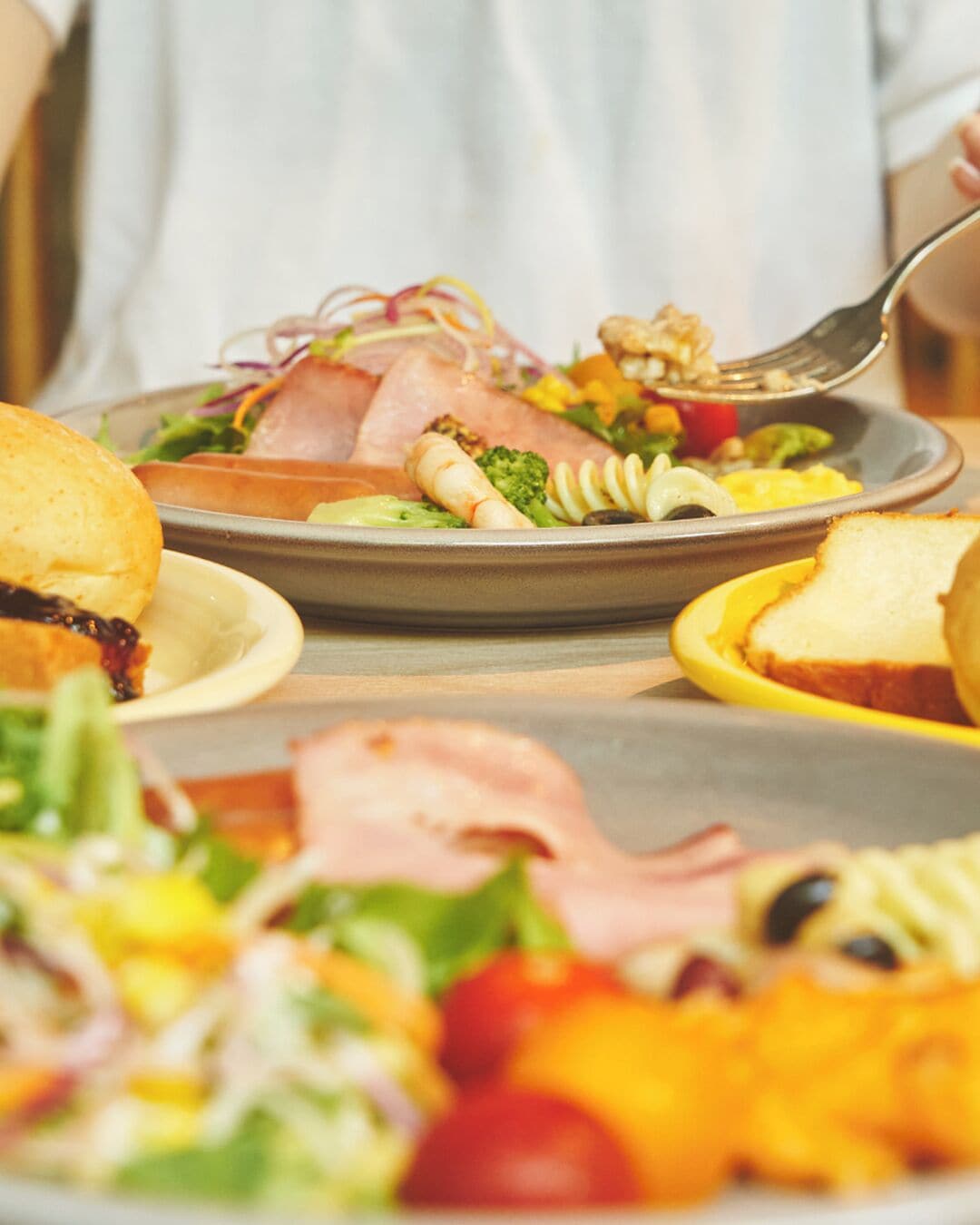 Un repas composé de différents plats, notamment une salade, du pain et une assiette avec un sandwich.