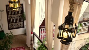 A staircase with a patterned carpet, hanging lanterns, and potted plants.