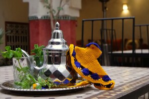 A tray with a metal pitcher, a glass, and a crocheted item on a checkered table.