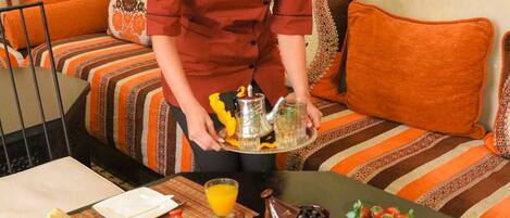 A breakfast setup with a variety of dishes and drinks on a table, including bread, fruits, and a teapot.