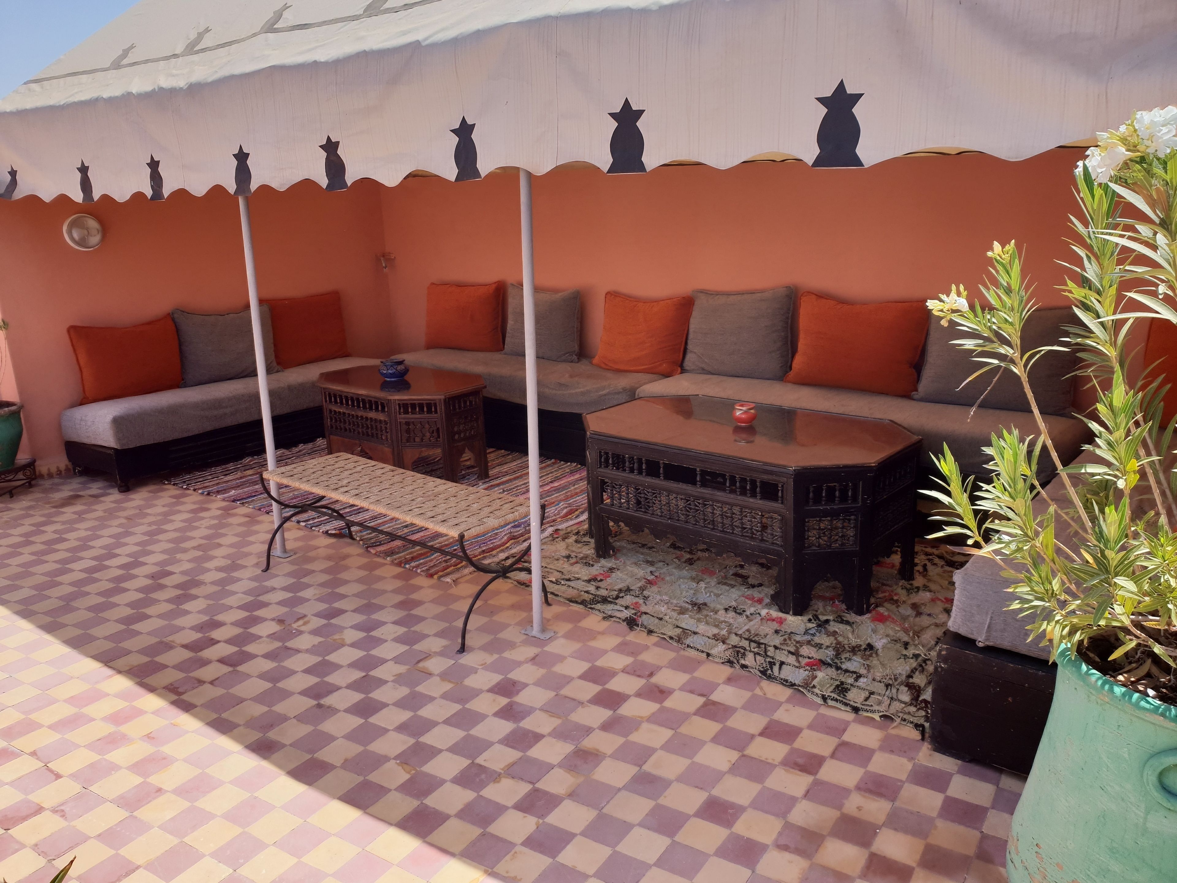 A cozy outdoor seating area with a checkered floor, a sofa, a coffee table, and a decorative umbrella.