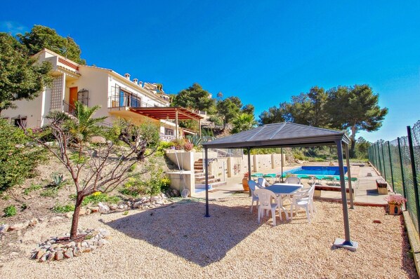 A house with a swimming pool, outdoor seating, and a pergola.