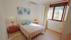 A bedroom with a bed, bedside tables, a chair, and a window with curtains. - Dos Soles  - sea view holiday home with private pool in Costa Blanca (Benissa)