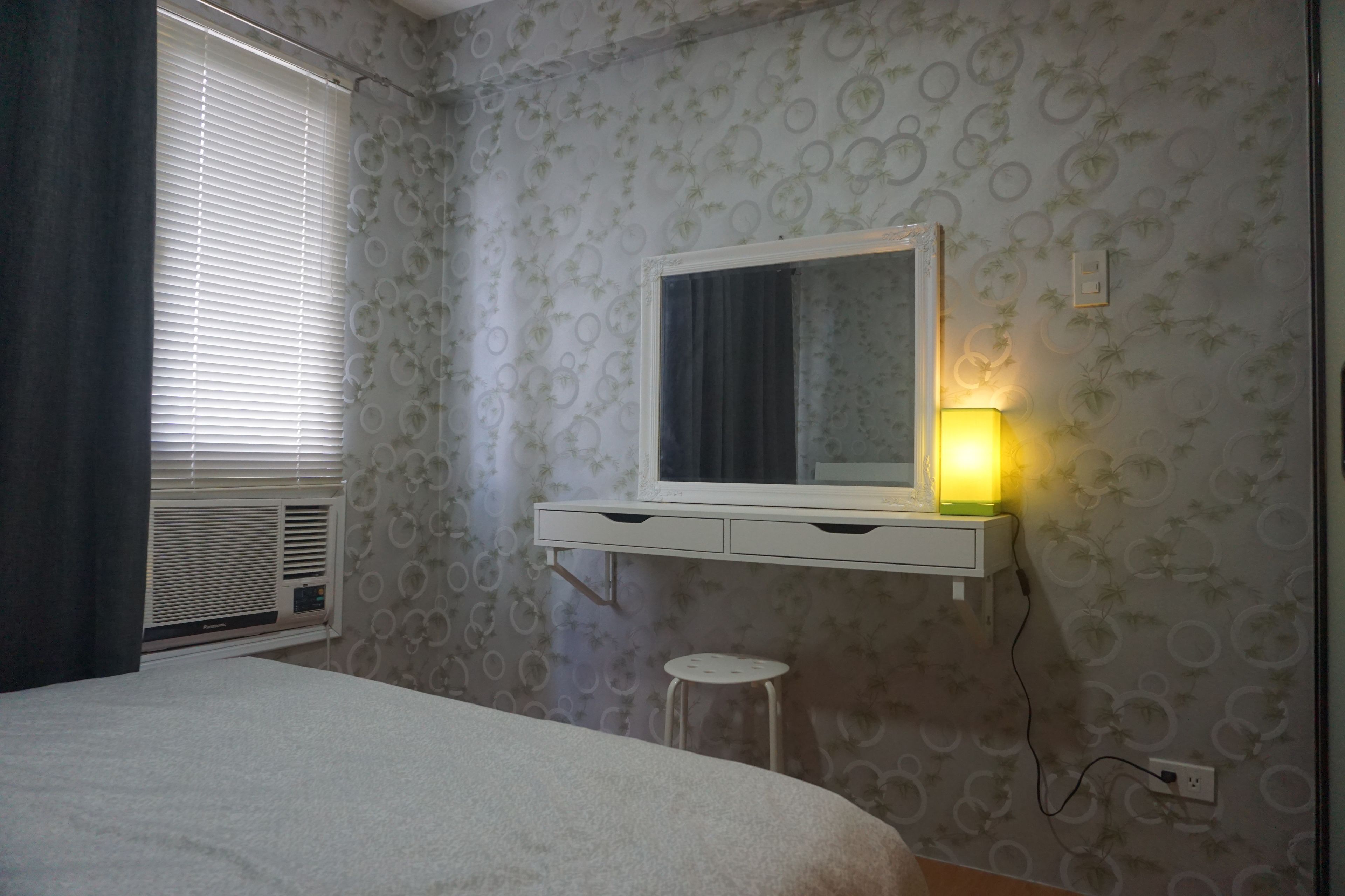 Une chambre à coucher avec un lit, une table de chevet, un miroir et une lampe.