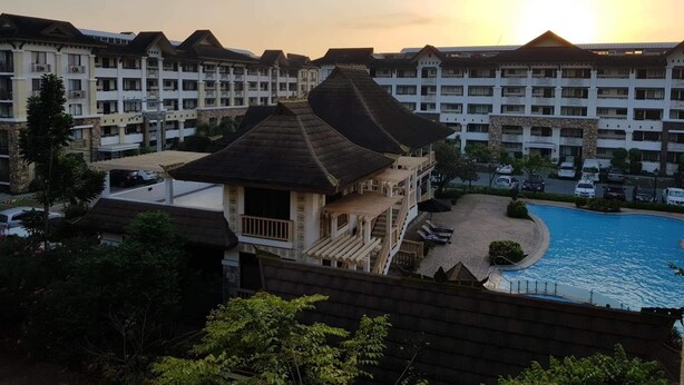 Un hotel con un edificio de estilo japonés tradicional en primer plano, una piscina y edificios modernos de varios pisos al fondo.