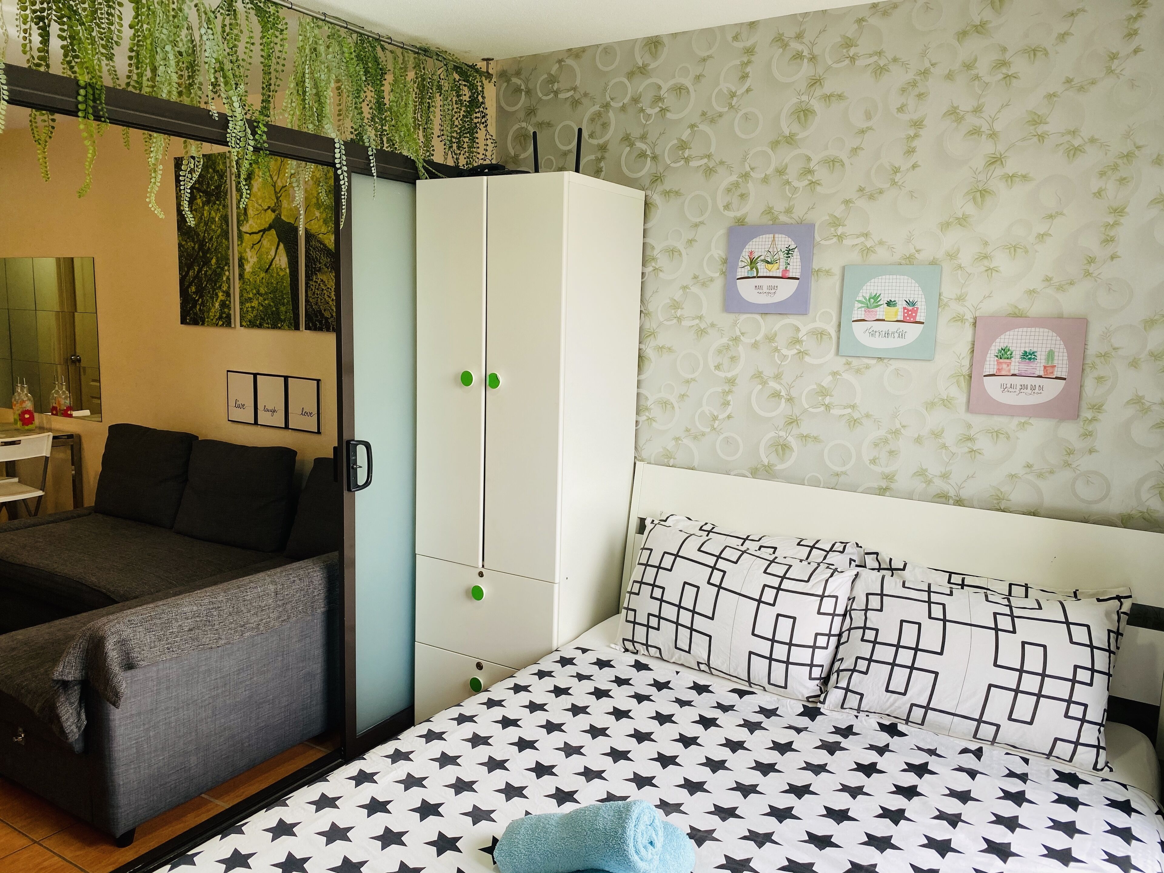 Une chambre à coucher avec un lit, une armoire, un bureau et une plante suspendue.