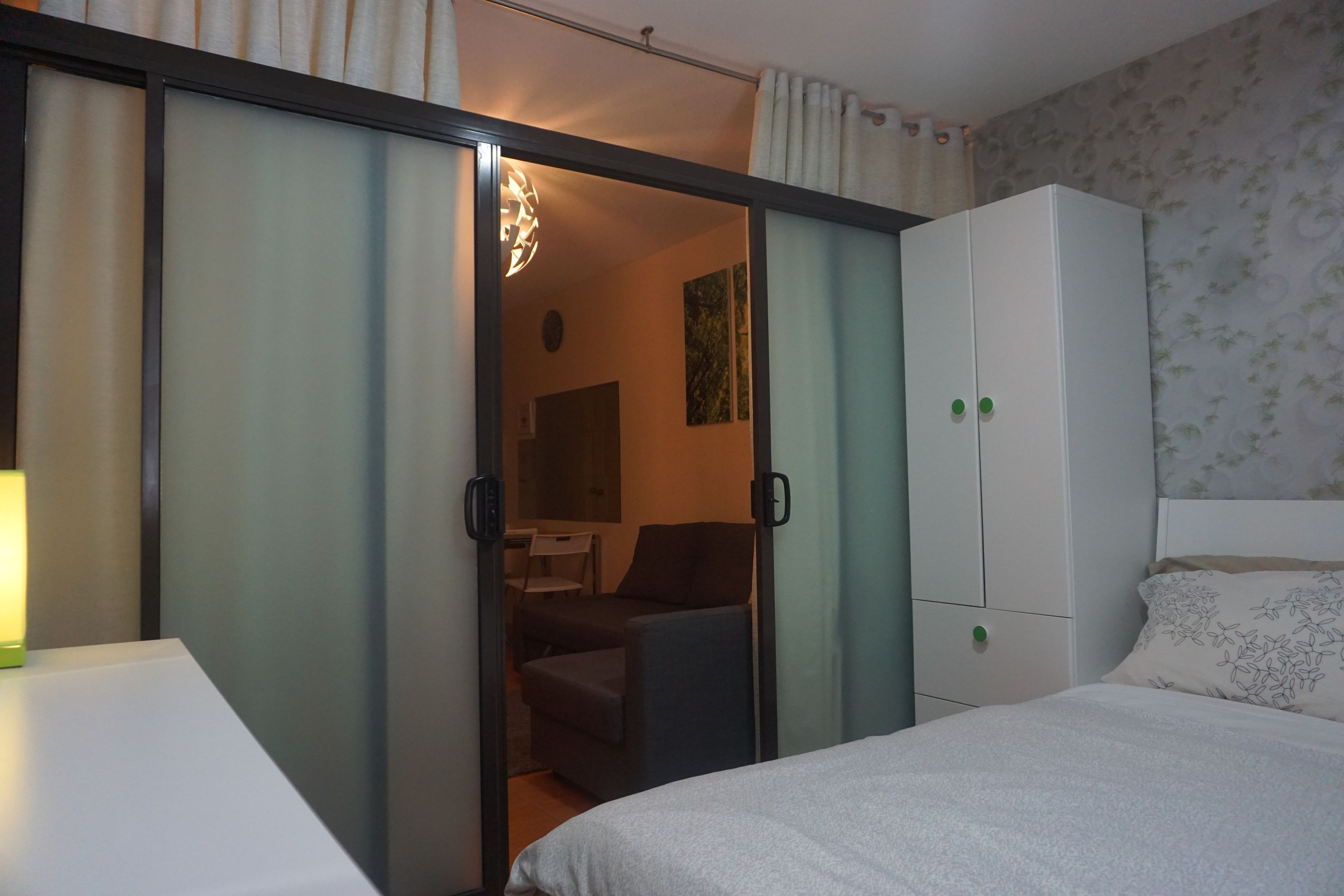 A bedroom with a bed, a wardrobe, a desk, and a chair.