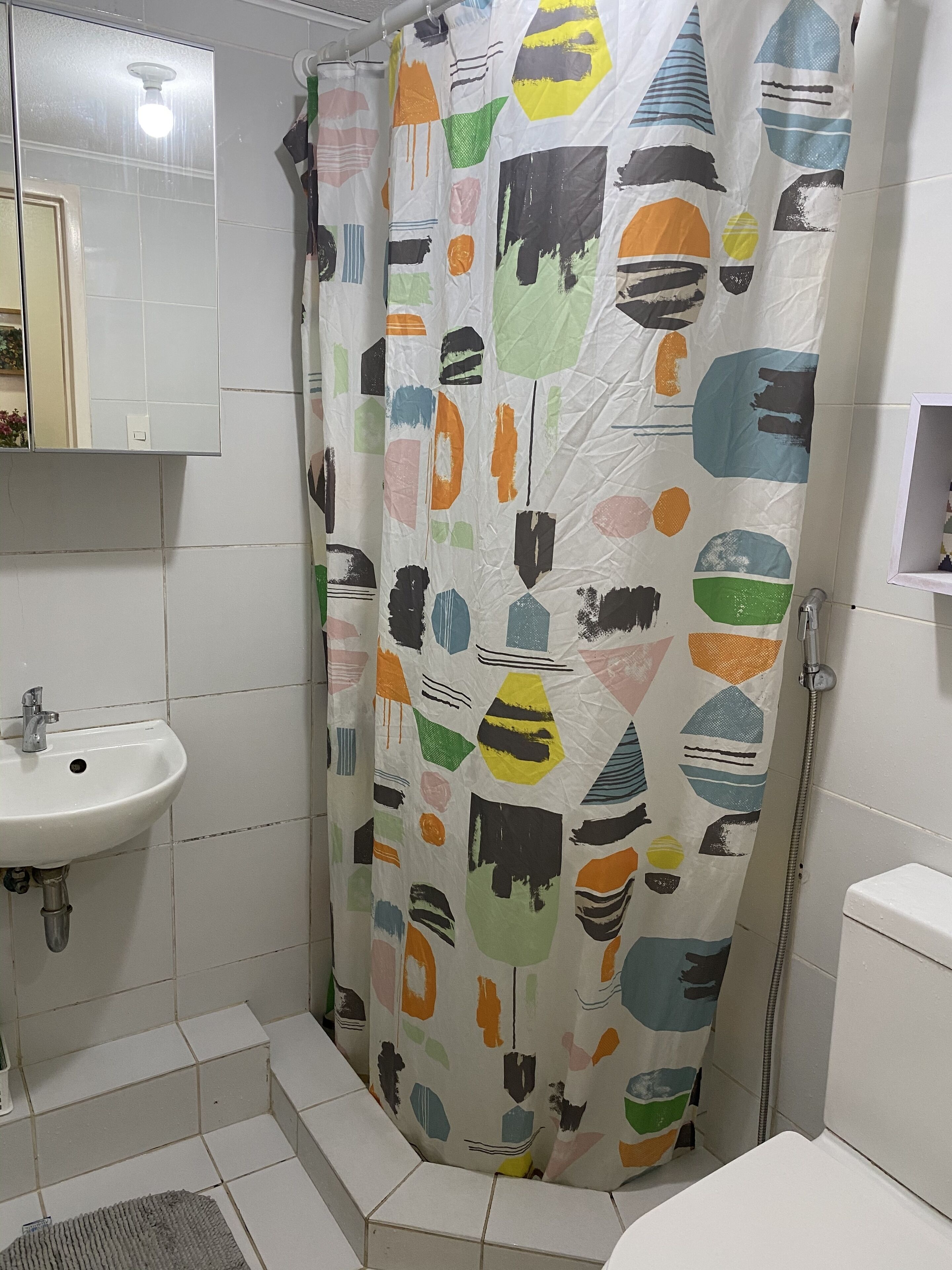 A bathroom with a shower curtain featuring abstract patterns, a white sink, and a toilet.