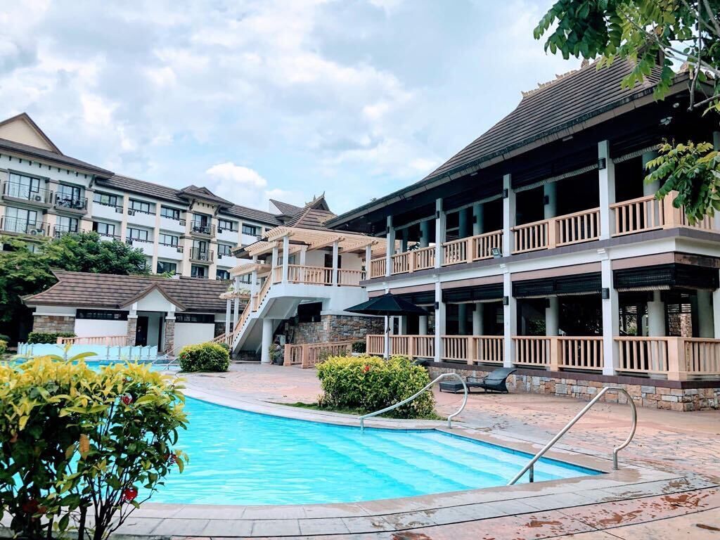 A hotel with a swimming pool, multiple balconies, and a covered outdoor area.