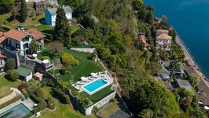 An aerial view of a coastal residential area with houses, a swimming pool, and a view of the sea. - Charming villa Il Motto with pool (Verbania)