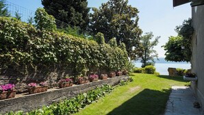 A garden with a stone wall, potted plants, and a view of the sea. - Charming villa Il Motto with pool (Verbania)