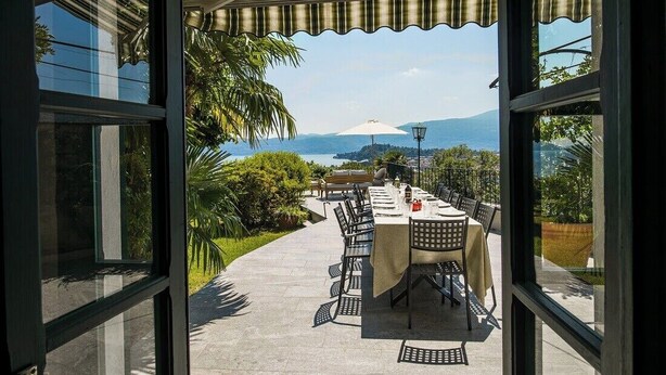 An outdoor dining area with a view of the sea and mountains. - Charming villa Il Motto with pool (Verbania)