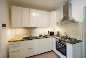 Kitchen features a stainless steel range hood, oven, and sink with faucet.