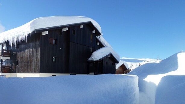 A large wooden building with a snow-covered roof, surrounded by snow. - Renovated cabin studio for 4, south balcony, garage included (Les Saisies)