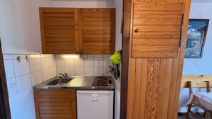 Eine kleine Küche mit Holzausstattung, Spüle, Geschirrspüler und einer Arbeitsplatte.