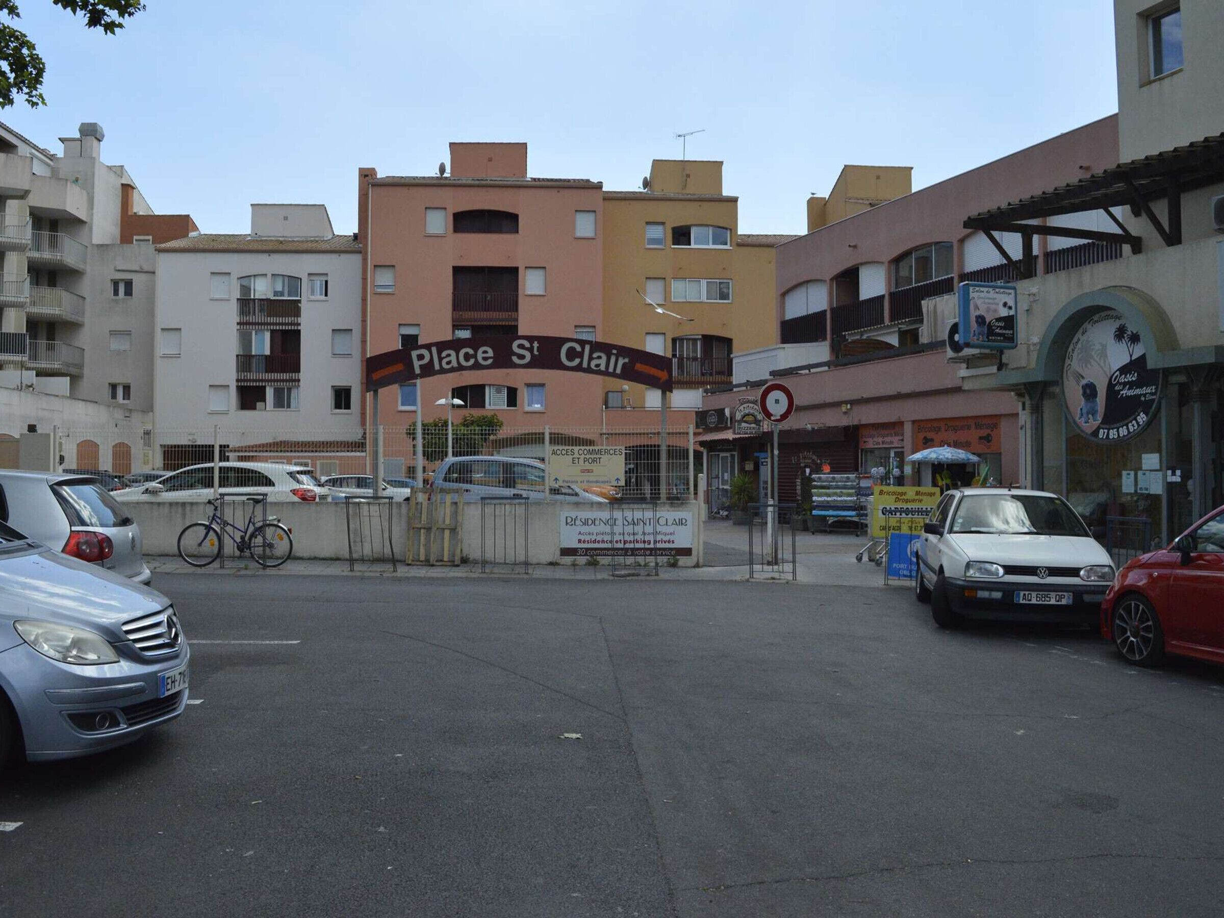 A street view with a sign for Place St Clair, a residential building, and parked cars.