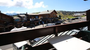 Un balcon donnant sur une ville, avec des bâtiments et une montagne en arrière-plan.