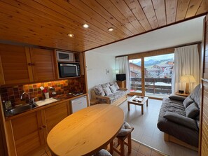 A cozy living room with a wooden dining table, a sofa, and a TV.