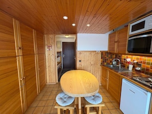 Une cuisine compacte avec des meubles en bois, un four à micro-ondes, un évier et un petit réfrigérateur.