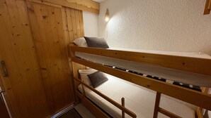 Un lit superposé avec une tête de lit en bois et une armoire dotée d’une poignée de porte.