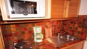 A kitchen with a microwave, coffee maker, stove, and sink. - Cozy studio cabin with balcony, sleeps 5, Les Saisies (Les Saisies)
