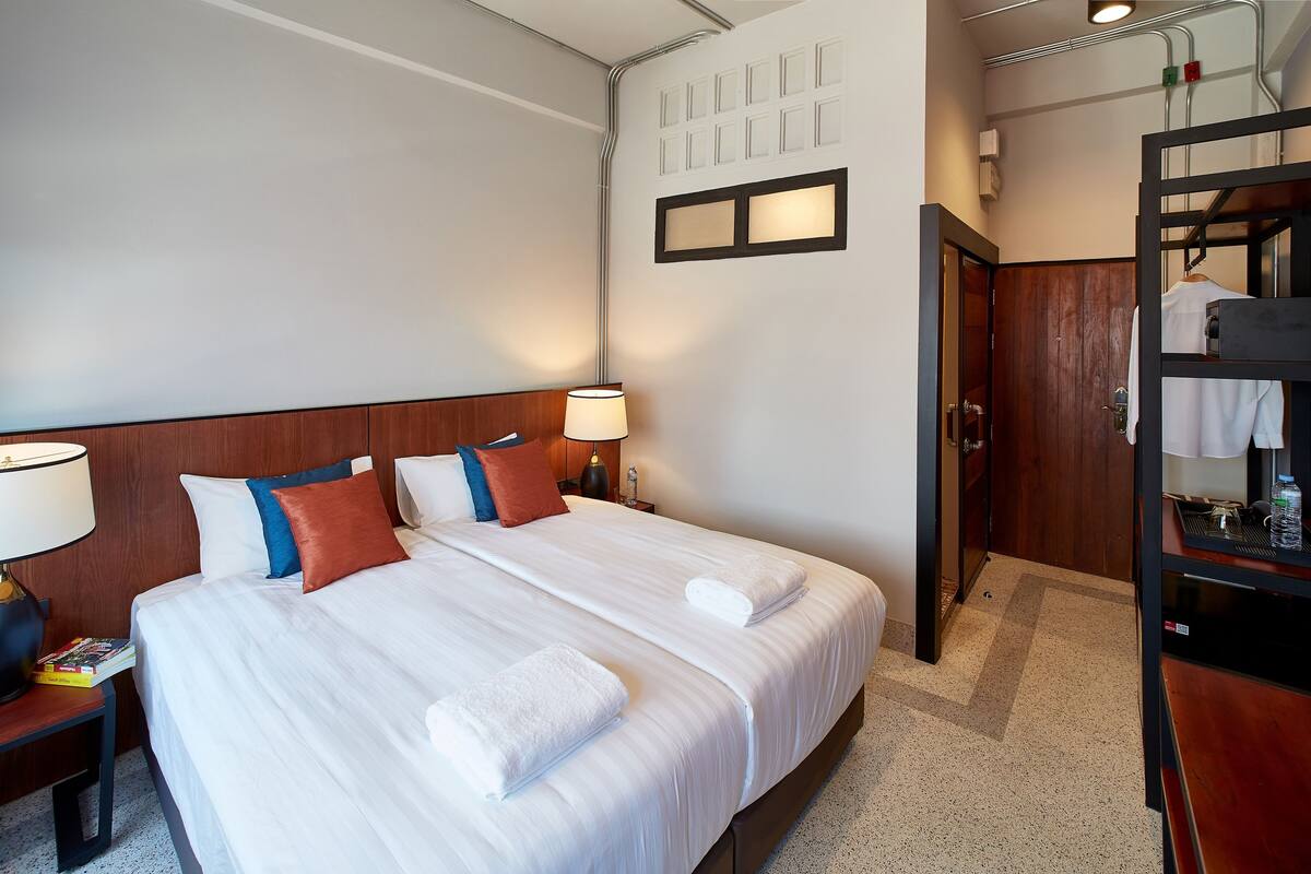 Ein Hotelzimmer mit Doppelbett, zwei Nachttischen mit Lampen, einem Holzkopfende, einem Kleiderschrank und einem Spiegel.