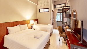 Habitación de hotel con dos camas, un escritorio con silla, un espejo y una ventana.