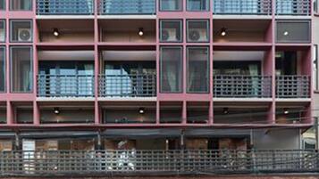 A multi-story hotel with a modern architectural design, featuring balconies on each floor and a ground-level entrance with a glass facade.