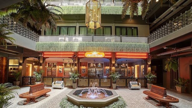 Un vestíbulo de hotel con una fuente central, zonas de estar y un bar.