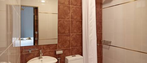 A bathroom with a white sink, a toilet, and a shower area.