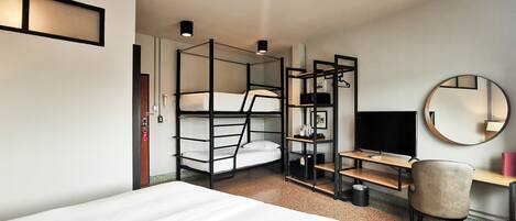 A modern hotel room with bunk beds, a desk, a chair, a round mirror, and a television.