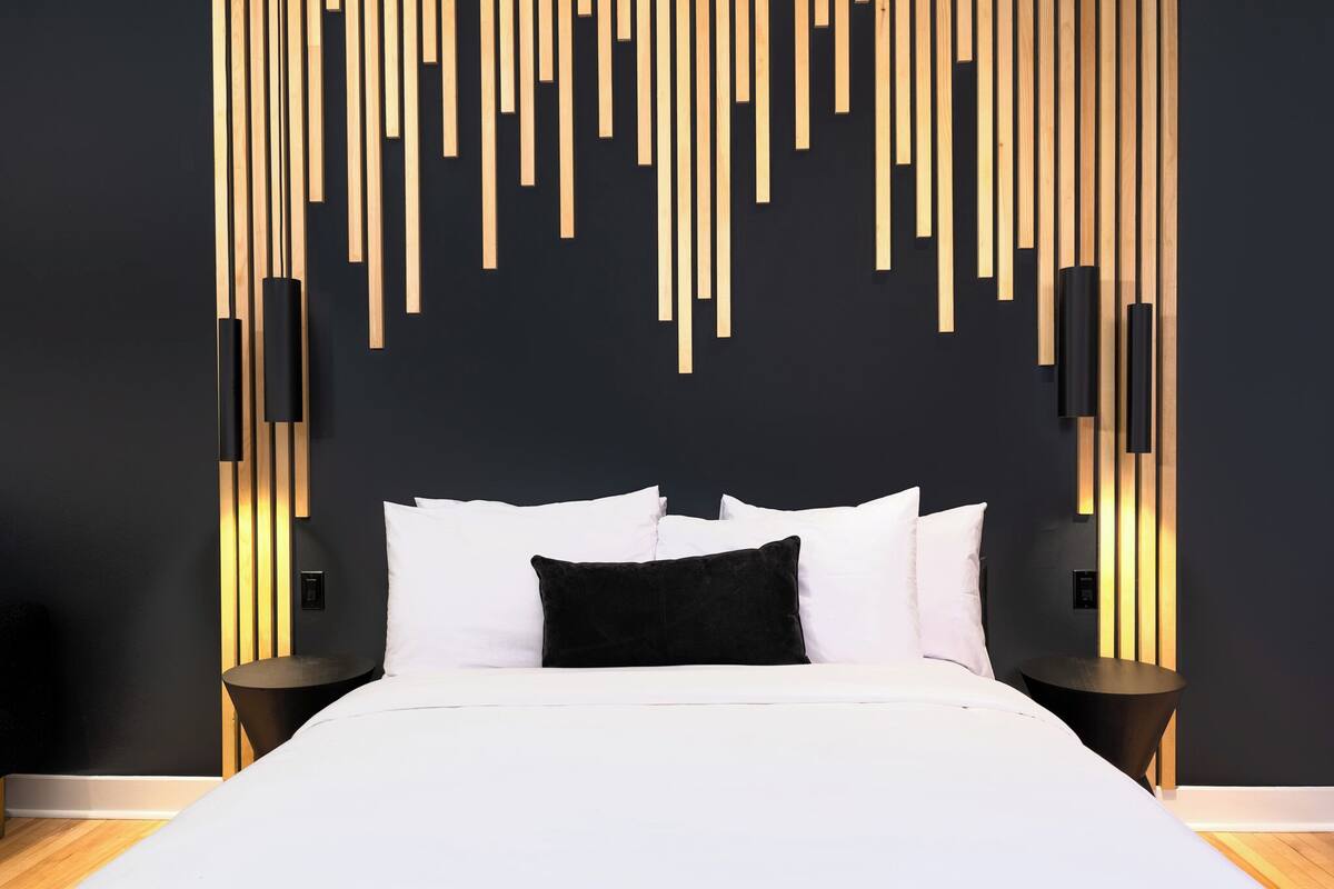 Un dormitorio moderno con cama, ropa de cama blanca y un diseño de panel de pared de madera original.