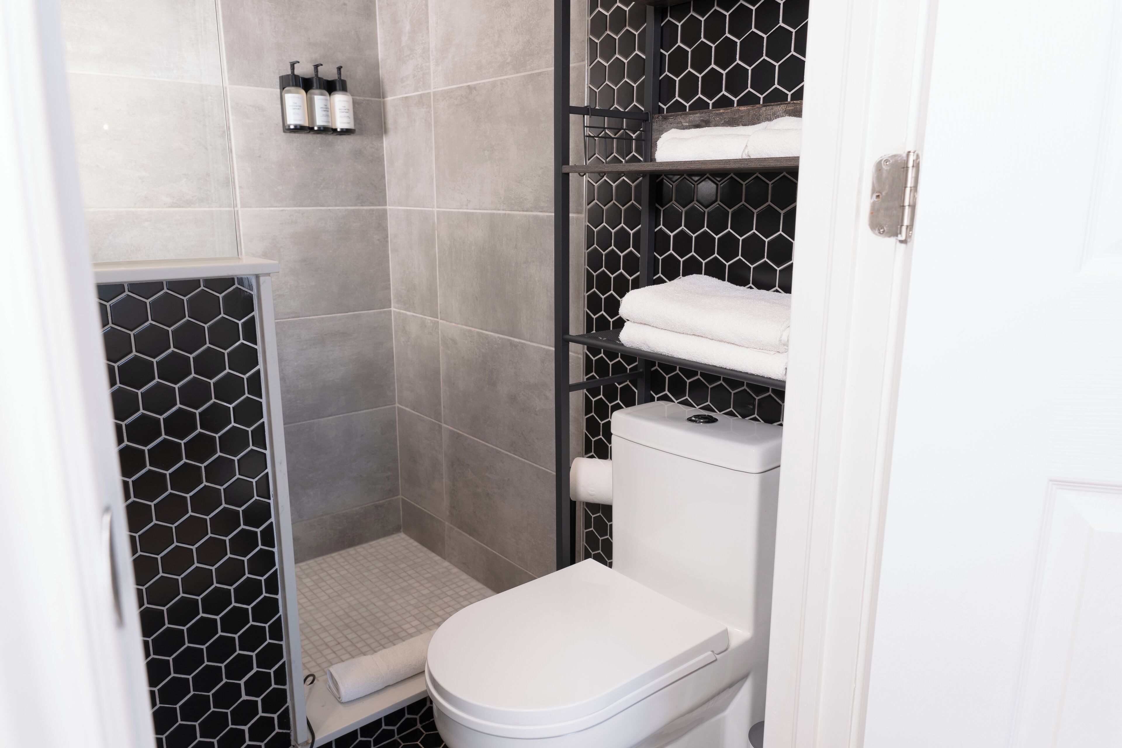 Un bagno con un motivo a esagoni sulle piastrelle, un water bianco e mensole con asciugamani.
