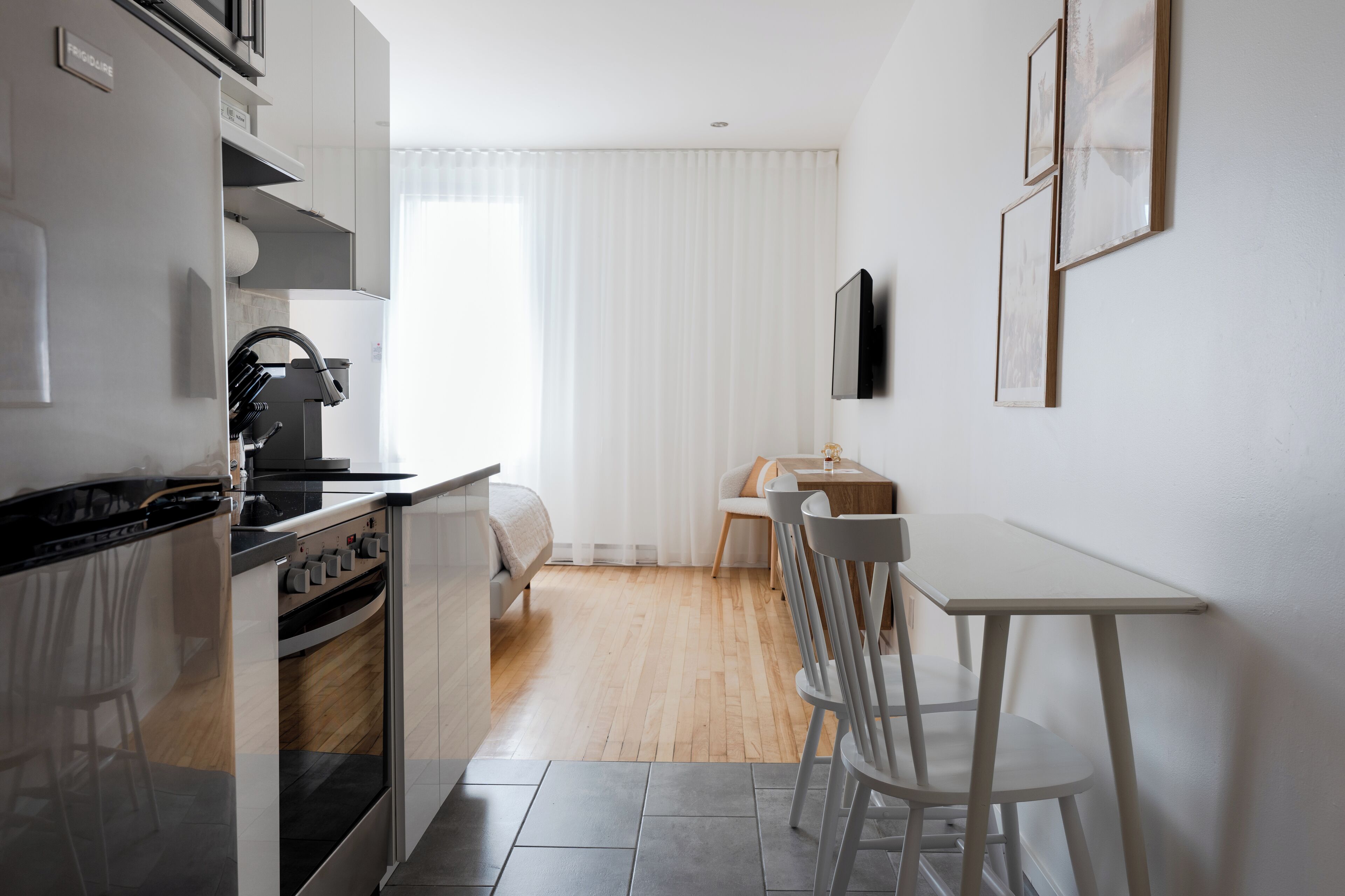 A modern kitchen with a built-in oven and a dining area with a table and chairs.
